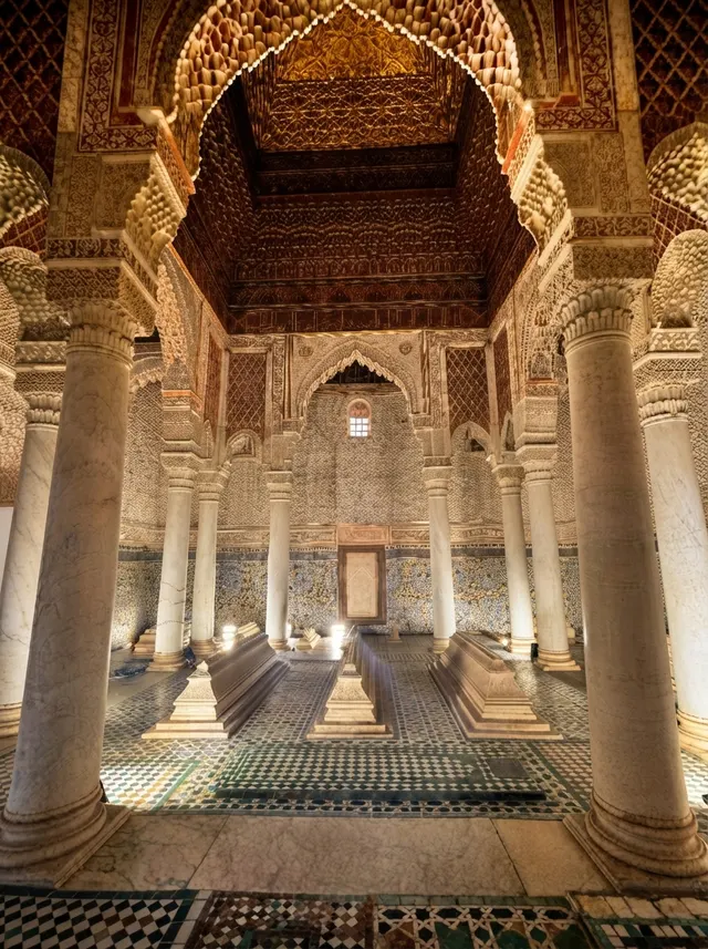 The Chamber of the Twelve Columns lit from the floor, marble tombs centred beneath the gilded ceiling