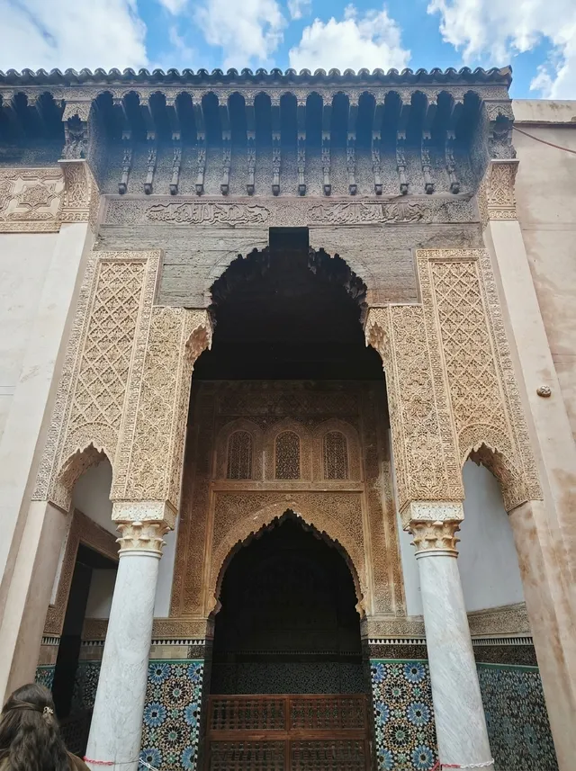 The carved cedar eaves and stucco portal of the mausoleum, seen from below against a blue sky