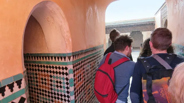 The narrow single-file entrance passage beside the Kasbah Mosque, tiled in zellige, with visitors filing through