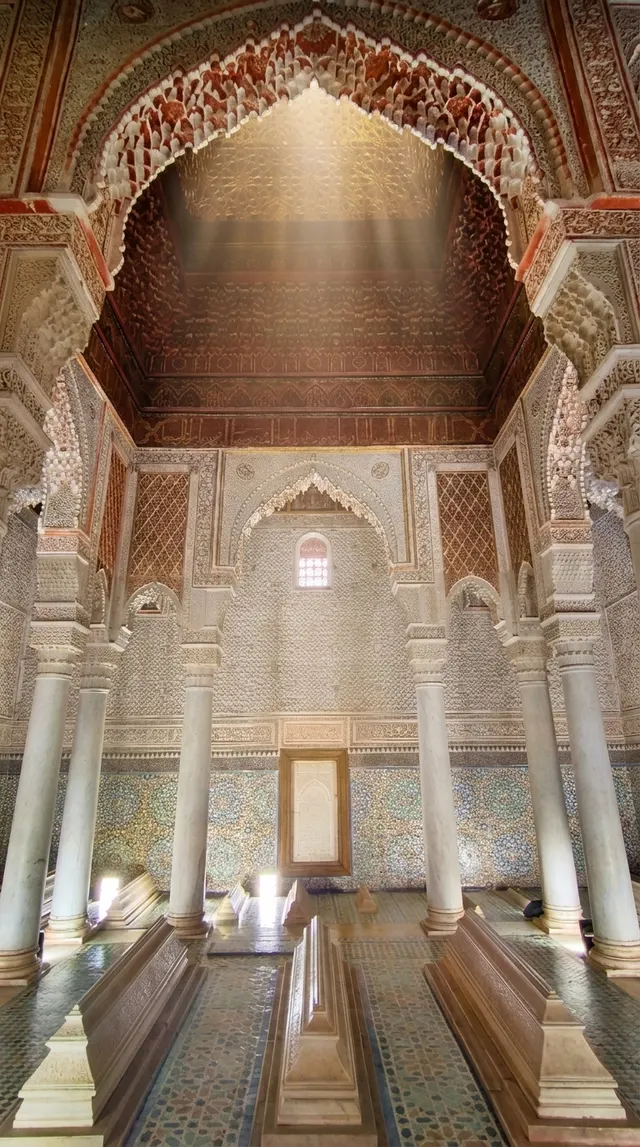 Daylight falling from the lantern onto the carved plaster and marble columns of the burial chamber