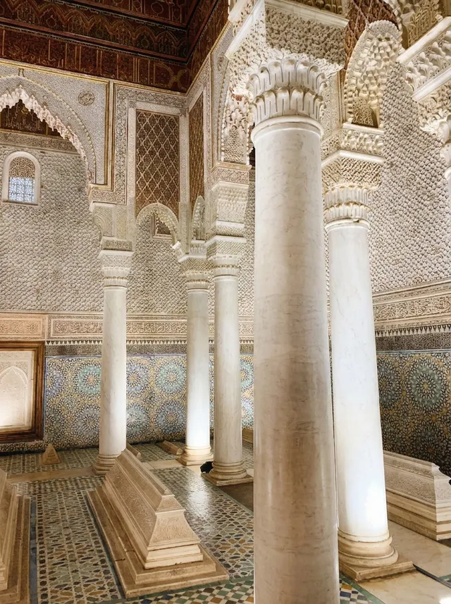 Carrara marble columns with carved stucco capitals, against walls of fine plasterwork and zellige