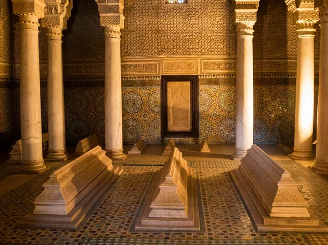 Marble tombstones on a zellige floor between the Carrara columns of the Chamber of the Twelve Columns